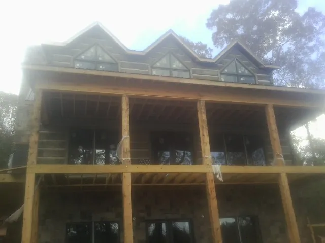 Dormers and porch framing on a large log home under construction — Roof Coating work by our crew in Marquette